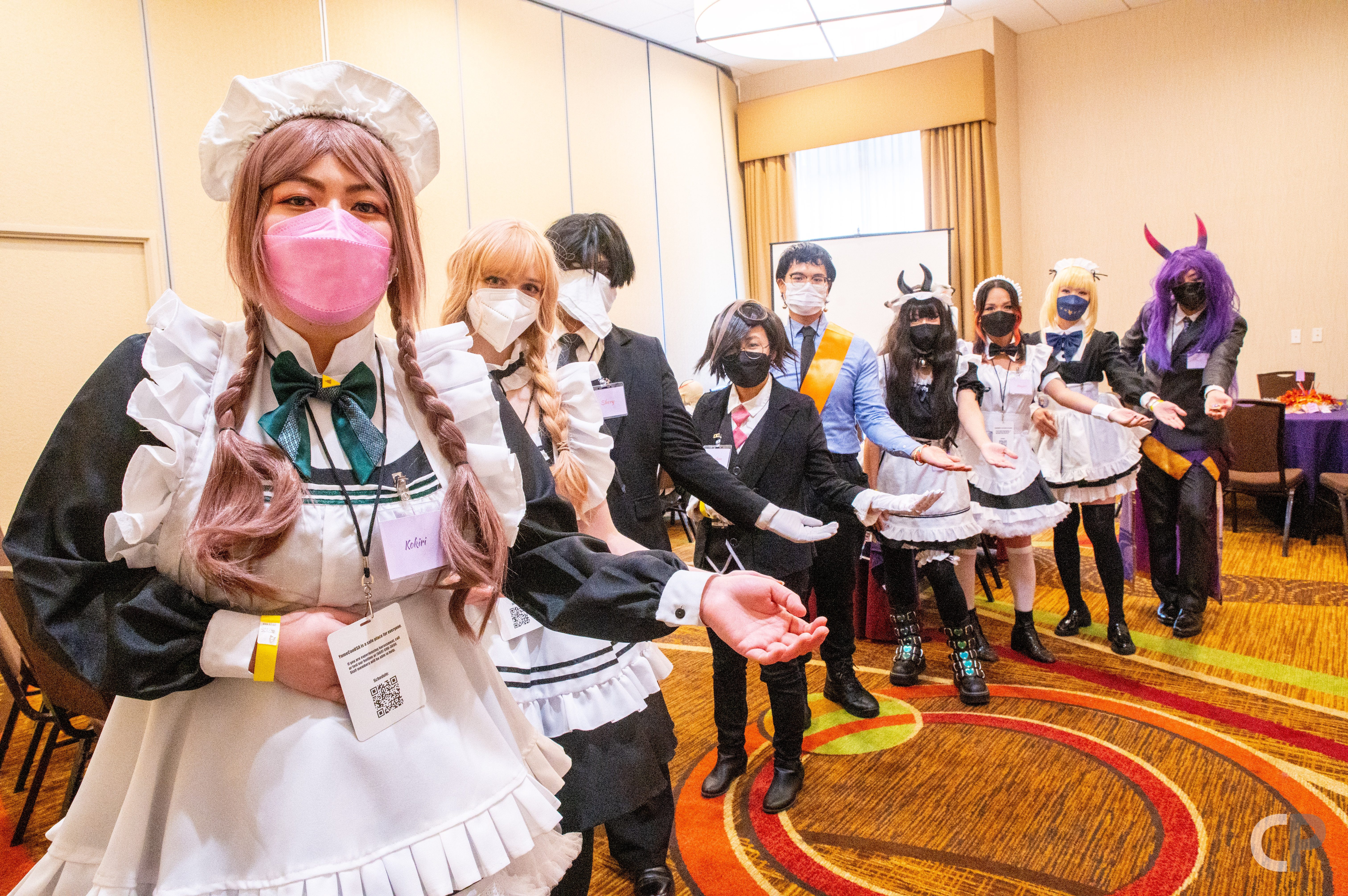 Maids and Butlers in YumeConUSA's Maid and Butler Cafe welcoming customers in.